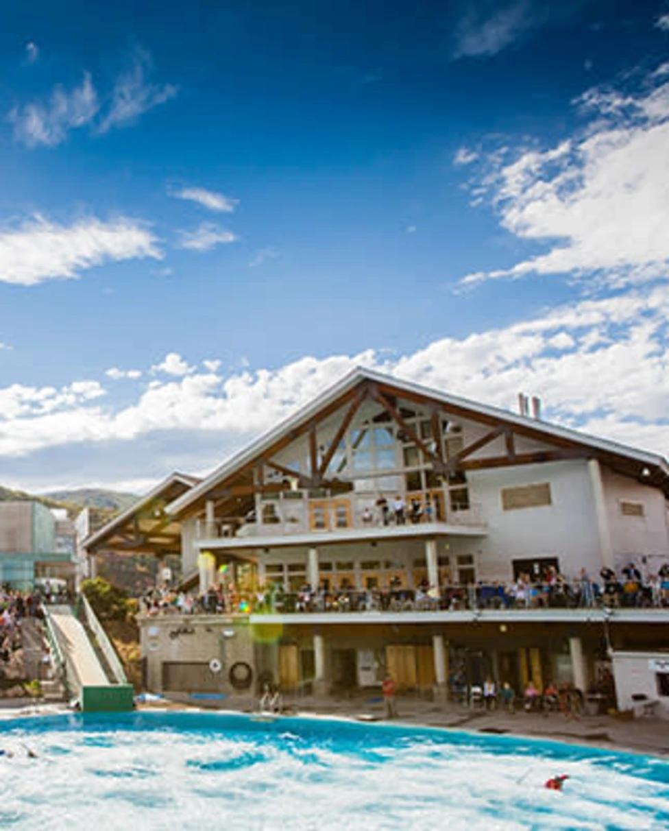 Utah Olympic Park with clear skies, the sun shining and people in the stands.