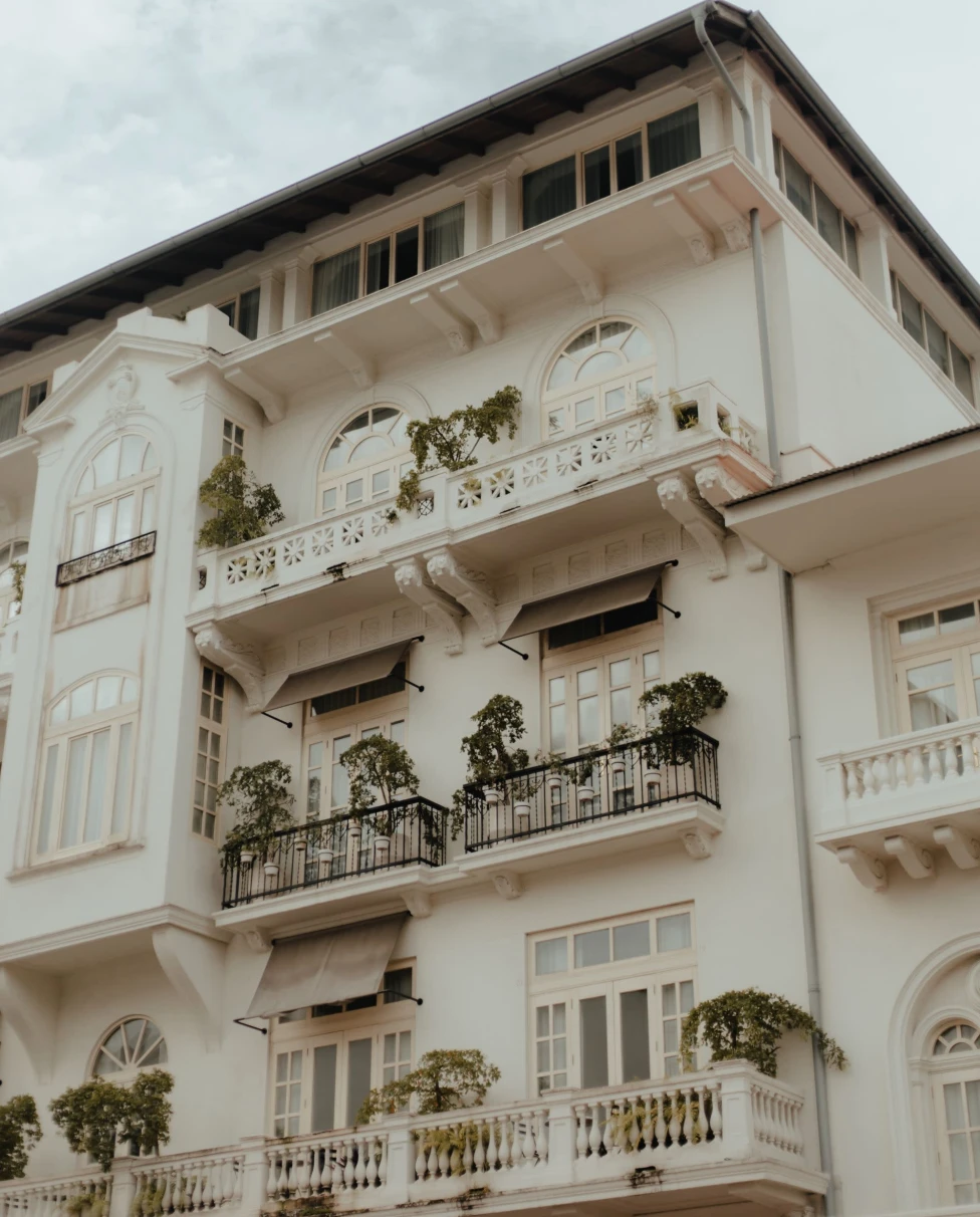 white historic building with small balconies against gray cloudy sky