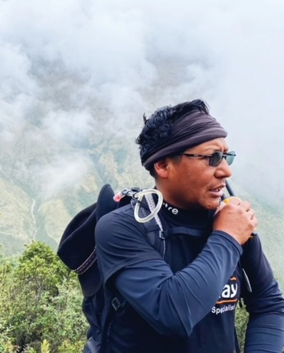 A man standing on a mountain in daytime.