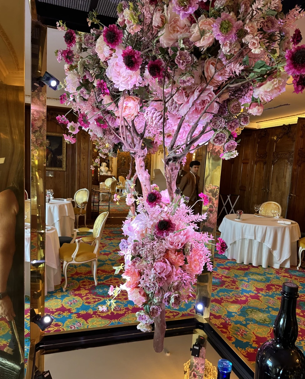 A vibrant floral arrangement with pink flowers in an eclectic interior space.