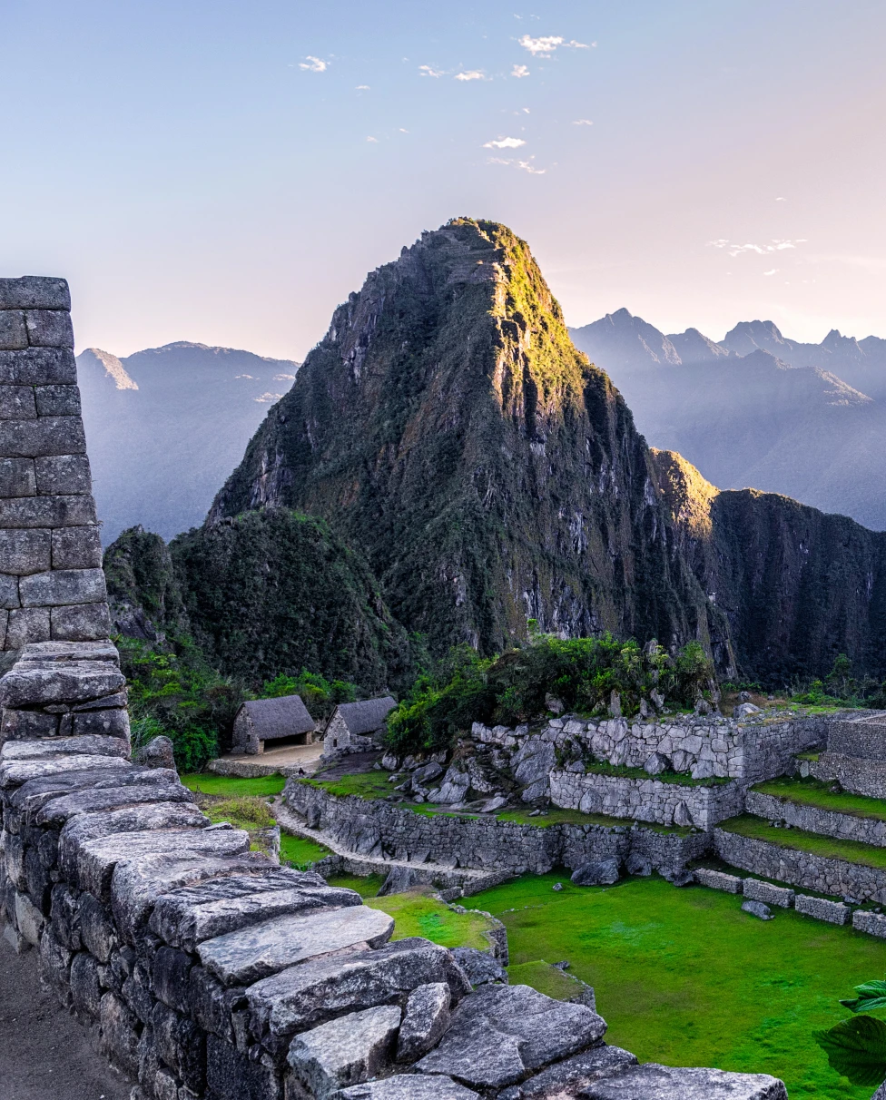 Machu Picchu in Peru green grass with grey stones and blue mountains with a beaming light