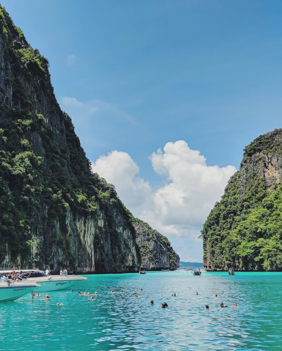 boat in body of water next to tall rocks during daytime