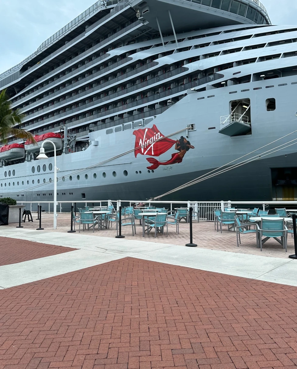 Virgin Voyages' ship Valiant Lady docked at a Port on a sunny day.