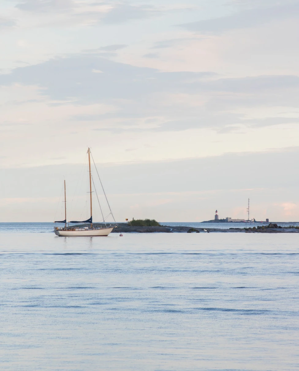 calm ocean at dusk with single moored sailboat