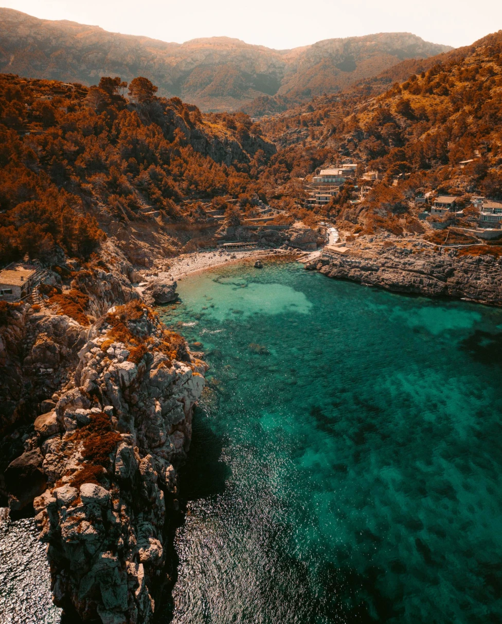 aerial view of vivid blue green waters of an island coast with clifss and mountainrange