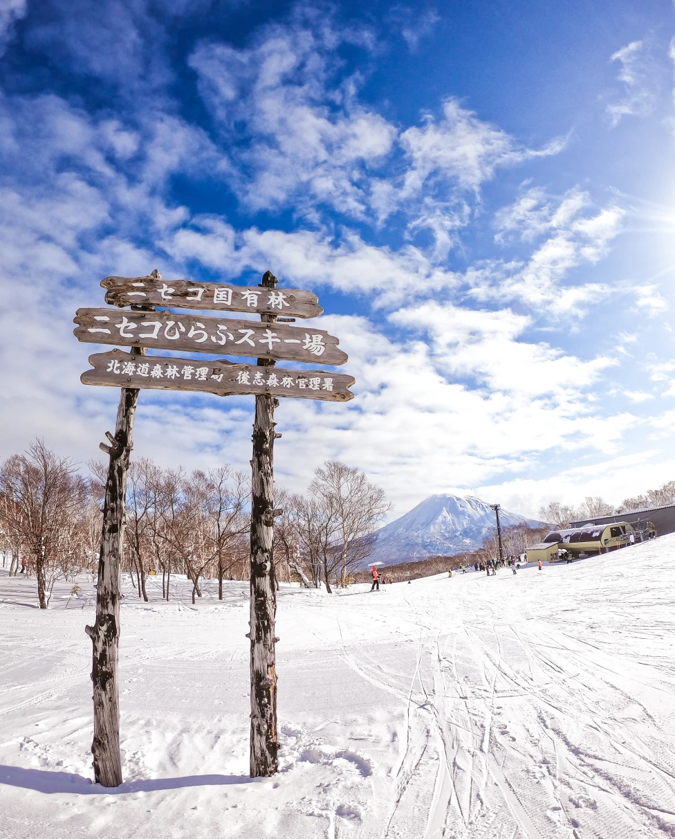 wood sign in the snow with mountain in the background during daytime