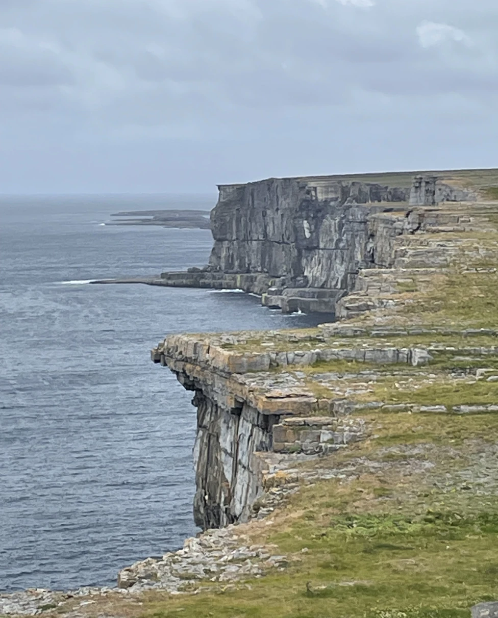 Cliffs edge next to a body of water during a cloudy day