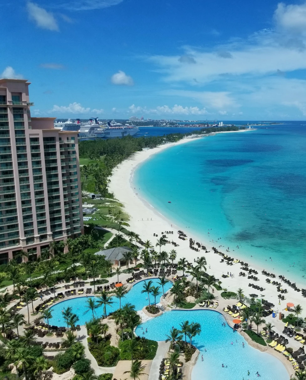 aerial view of blue ocean and white sand next to tall buildings