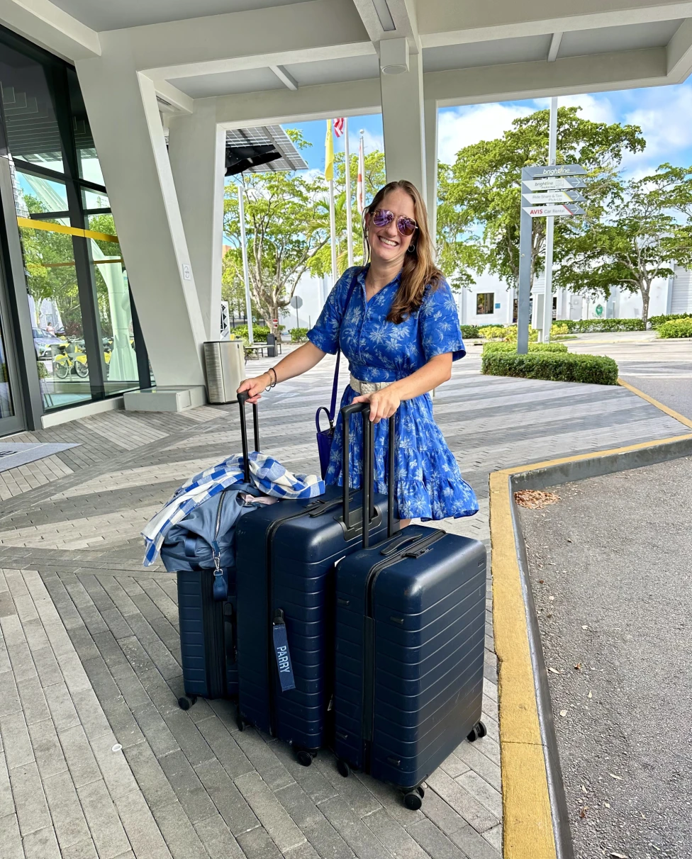 A woman standing with three suitcases.