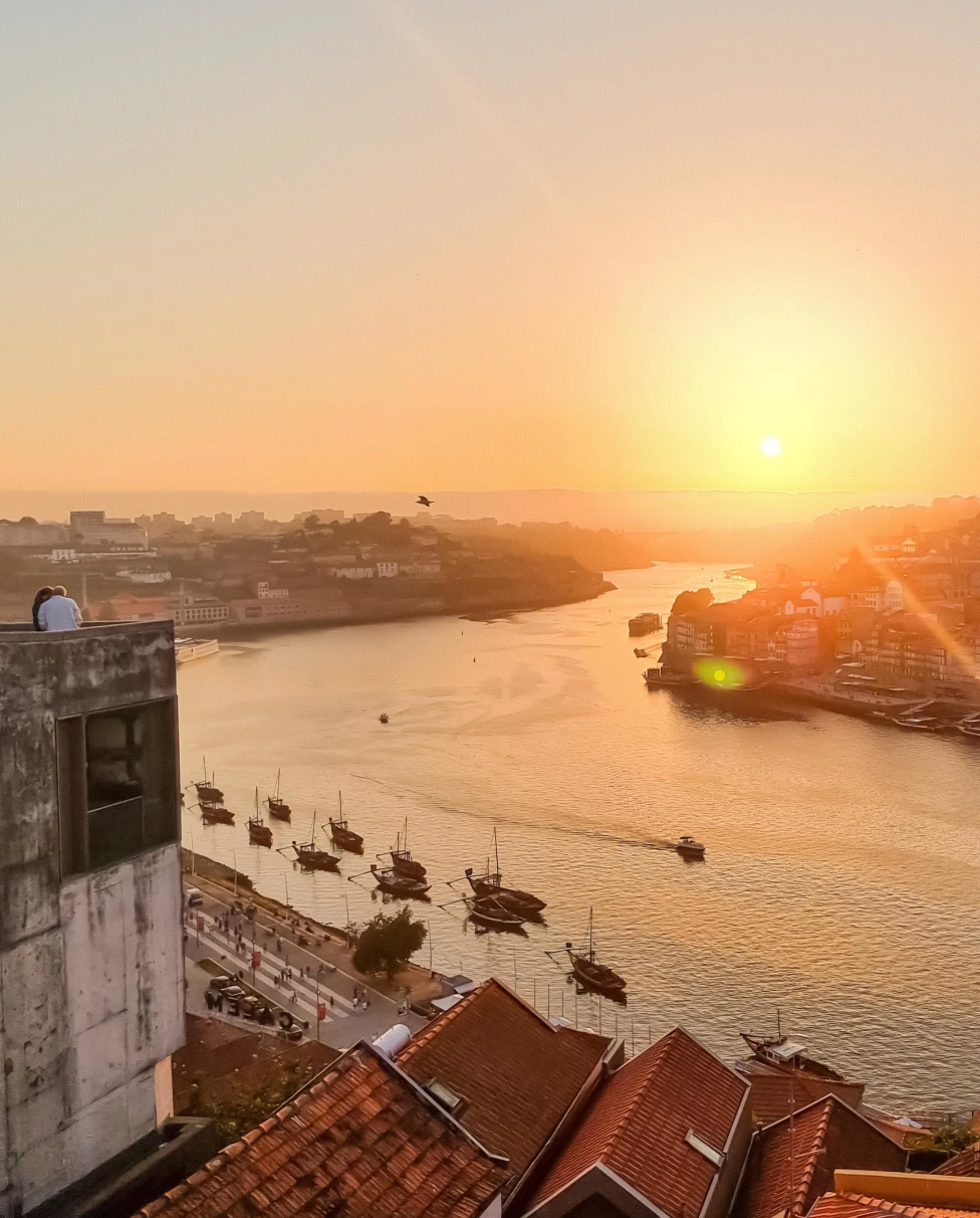 view atop an old coastal city during a vidid orange sunset with boats on the calm ocean