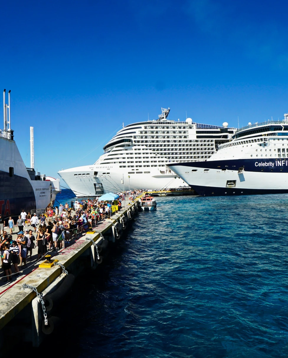 Travelers on the dock by cruise ships on the water.