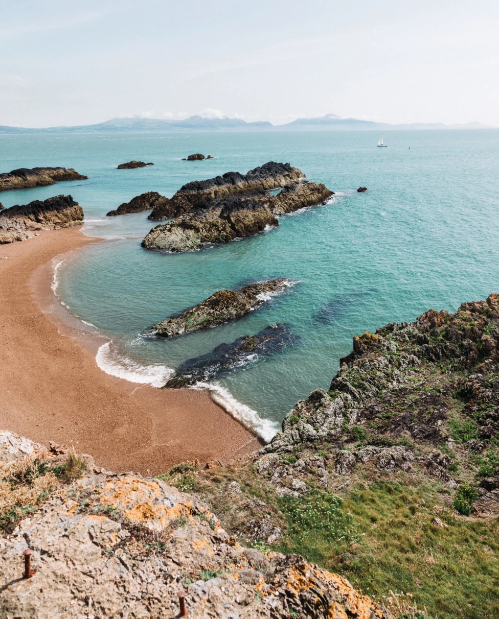 a cliff onto a sand beach and vast ocean on a sunny day