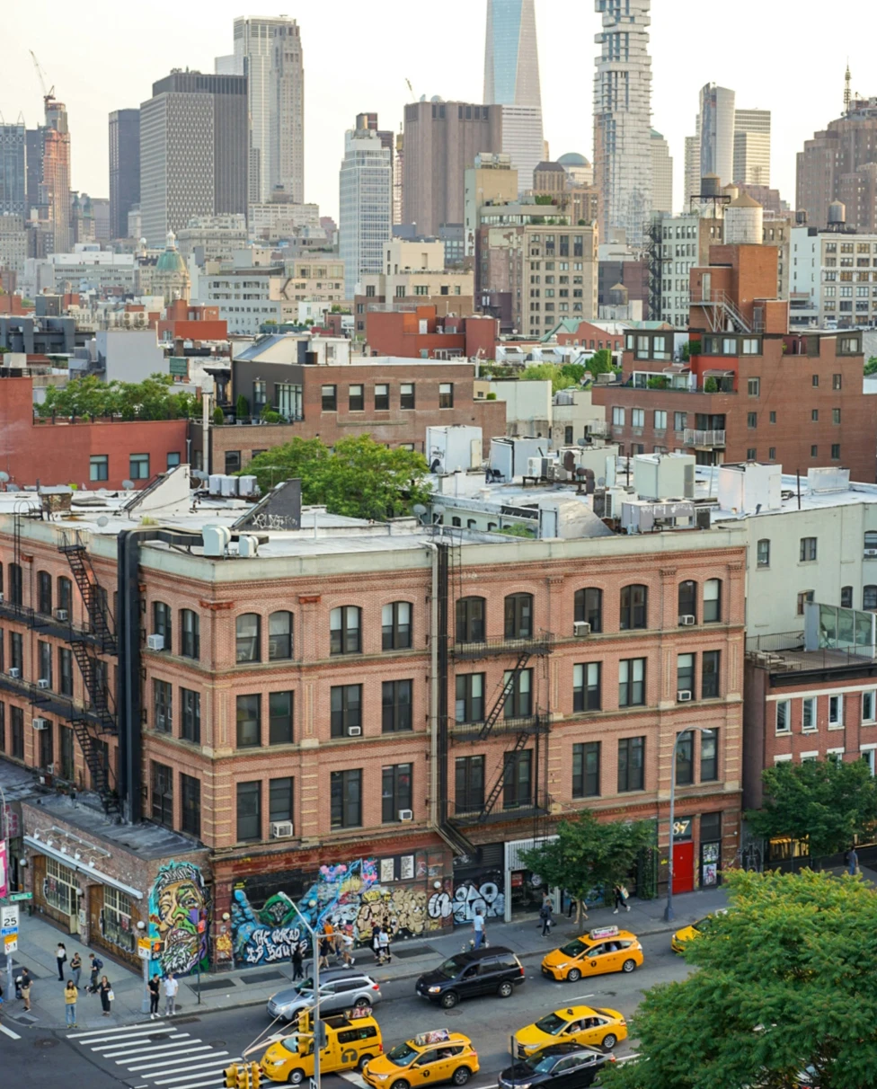An aerial view of the New York city skyscrapers and smaller brick buildings and yellow taxis in the street