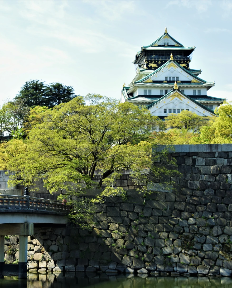 Castle in Osaka perched on hill with bridge in foreground