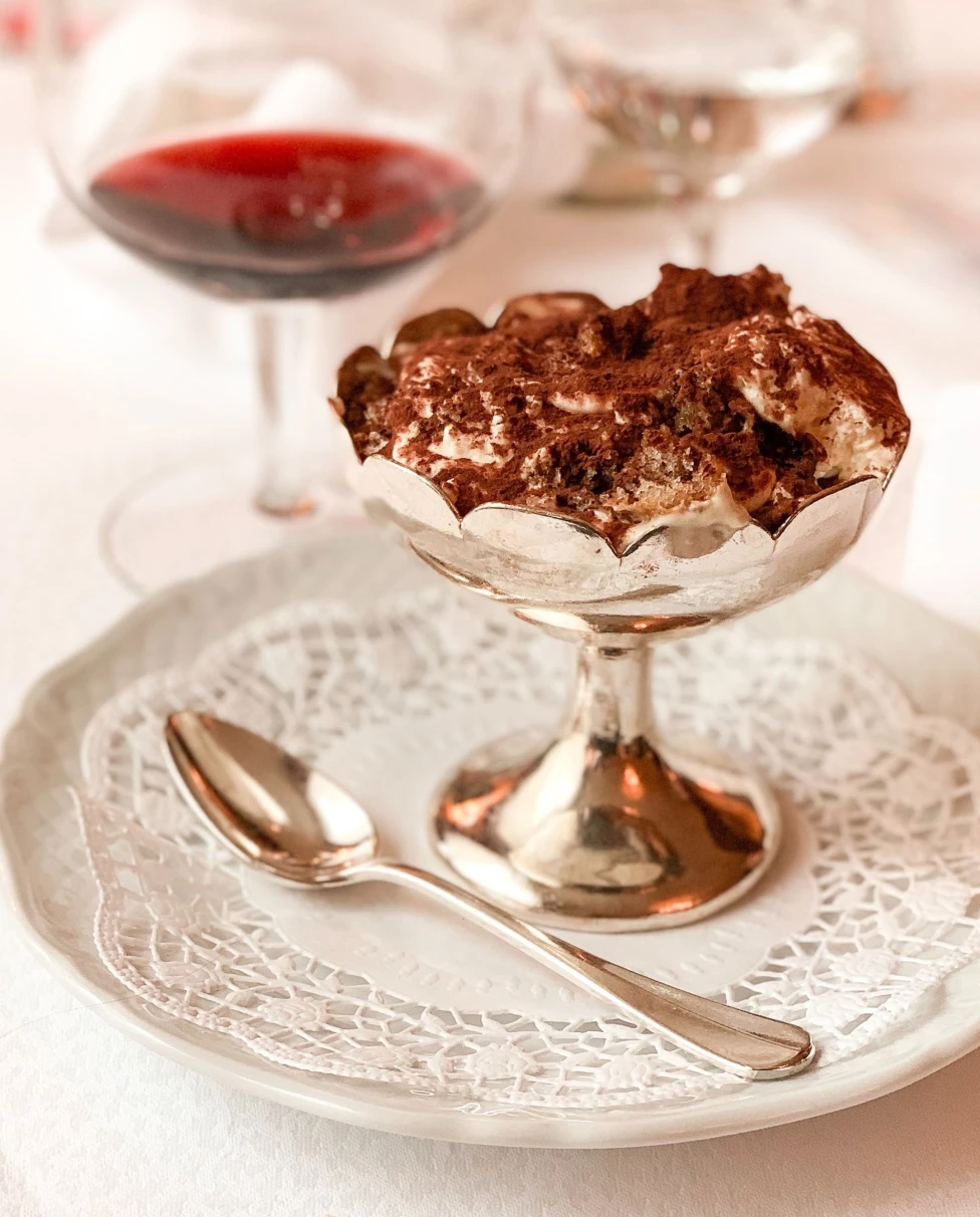 A picture of gold goblet filled dessert next to a wine glass.