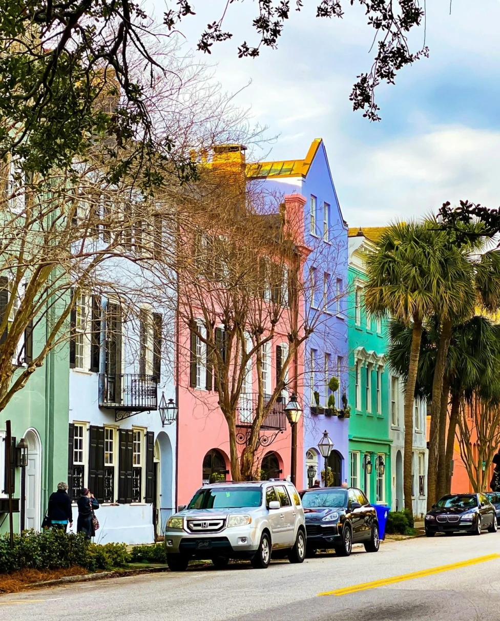 A view of colorful buildings, cars parked and trees.