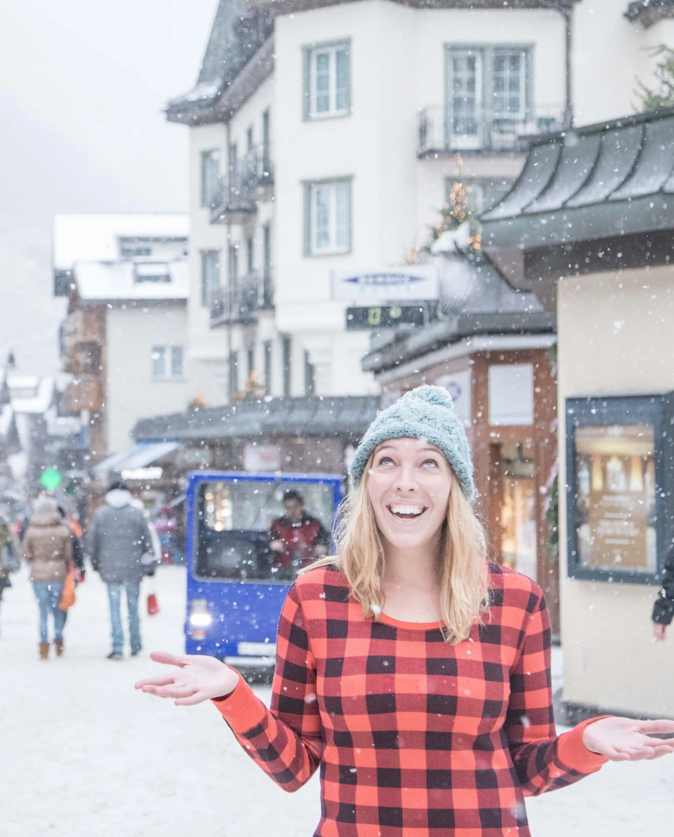 A woman enjoying snowfall in a red and black dress.