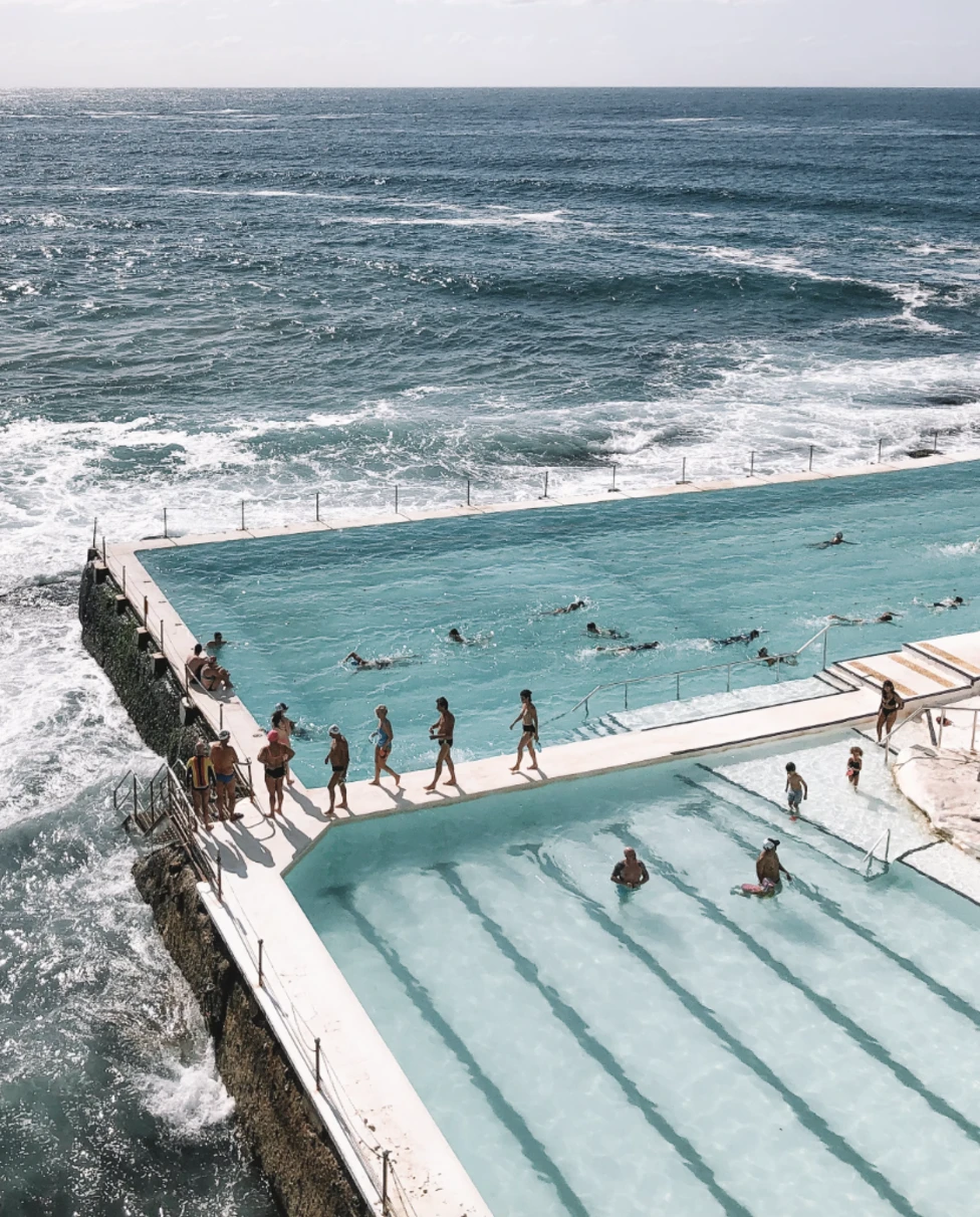 A view of people standing near a swimming pool and ocean.