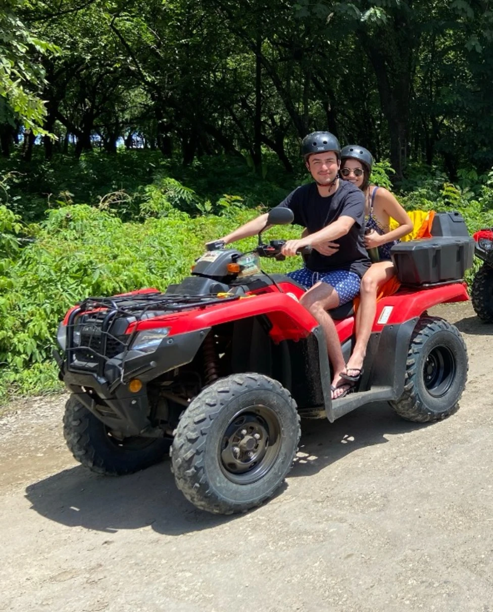A group of adventurers on ATVs, ready for an off-road journey amidst a forested trail on a sunny day.