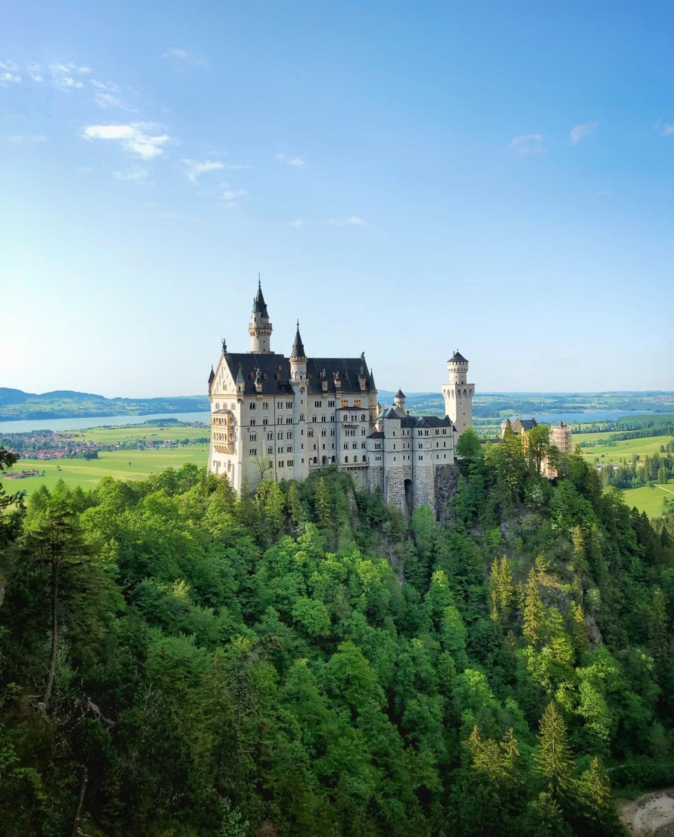 Neuschwanstein Castle surrounded by trees with blue skies in Bavaria