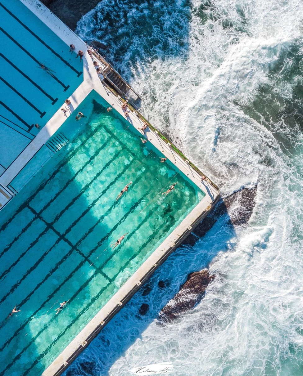 aerial view of people swimming in a pool near the ocean