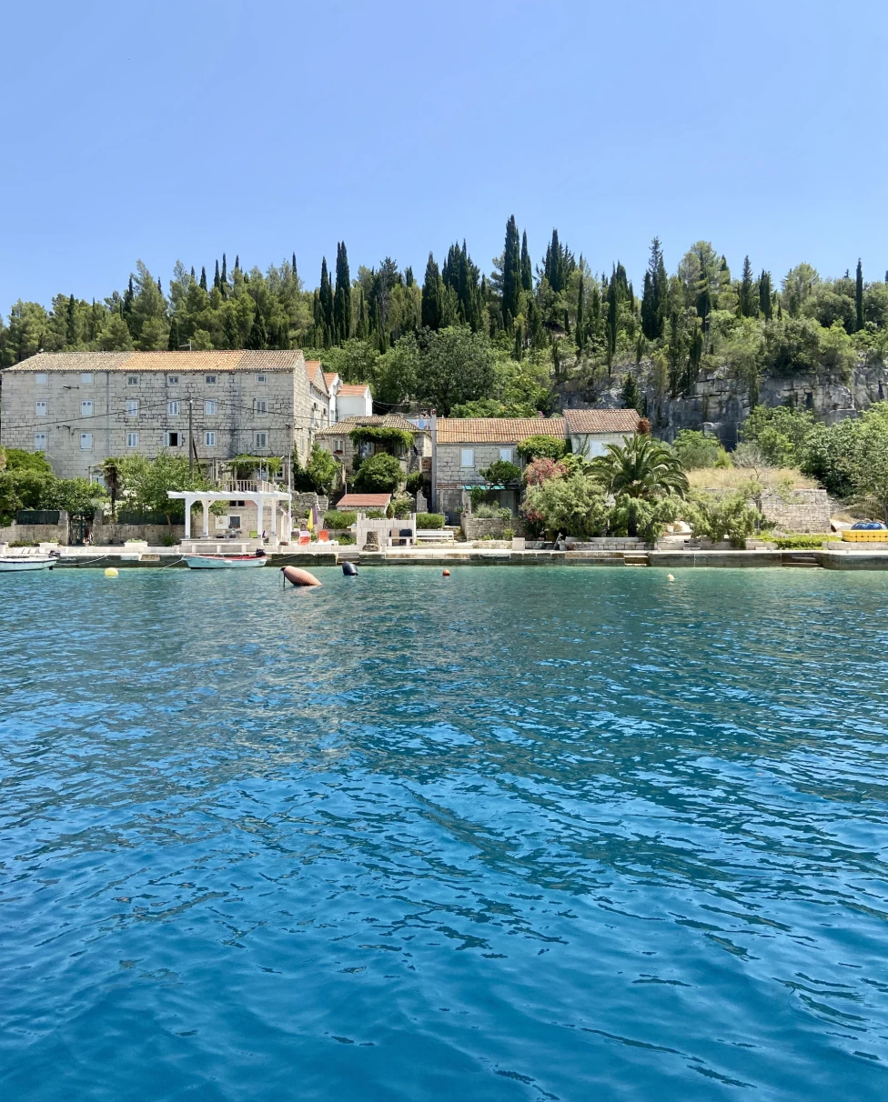 The image offers a peaceful waterfront scene, blending architecture and nature under a clear blue sky.