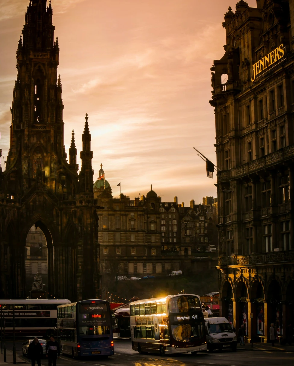 The image captures a sunset over a bustling city street with historic architecture and the prominent signage of ‘Jenners’.