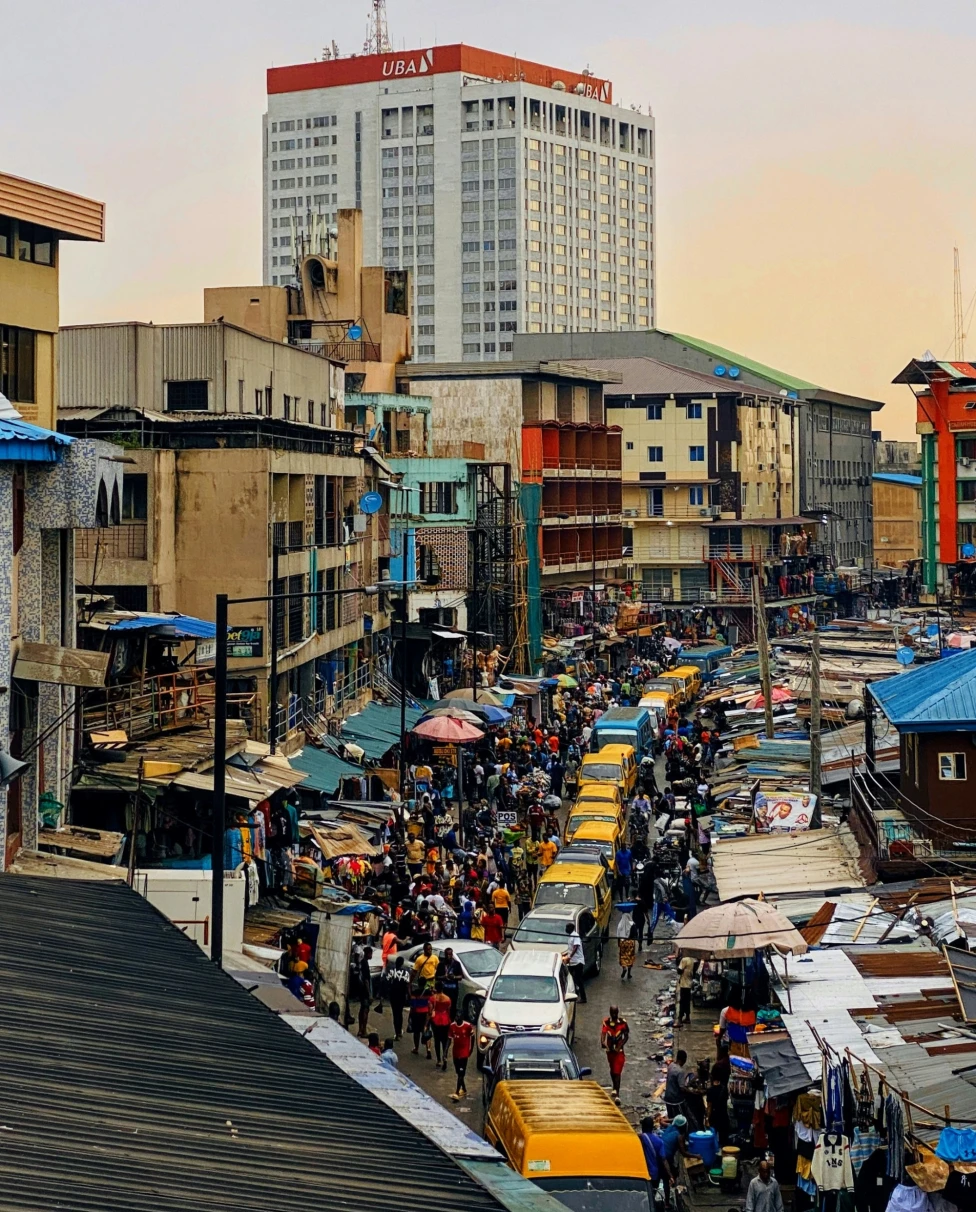A vibrant street market bustling with activity, overlooked by a tall building.