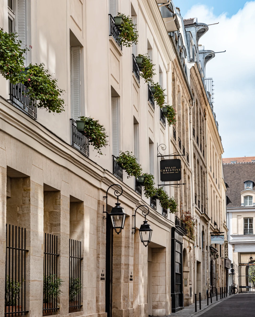 The Relais Christine hotel in the 6th arrondissement of Paris, a beige building with green plants on the balconies.