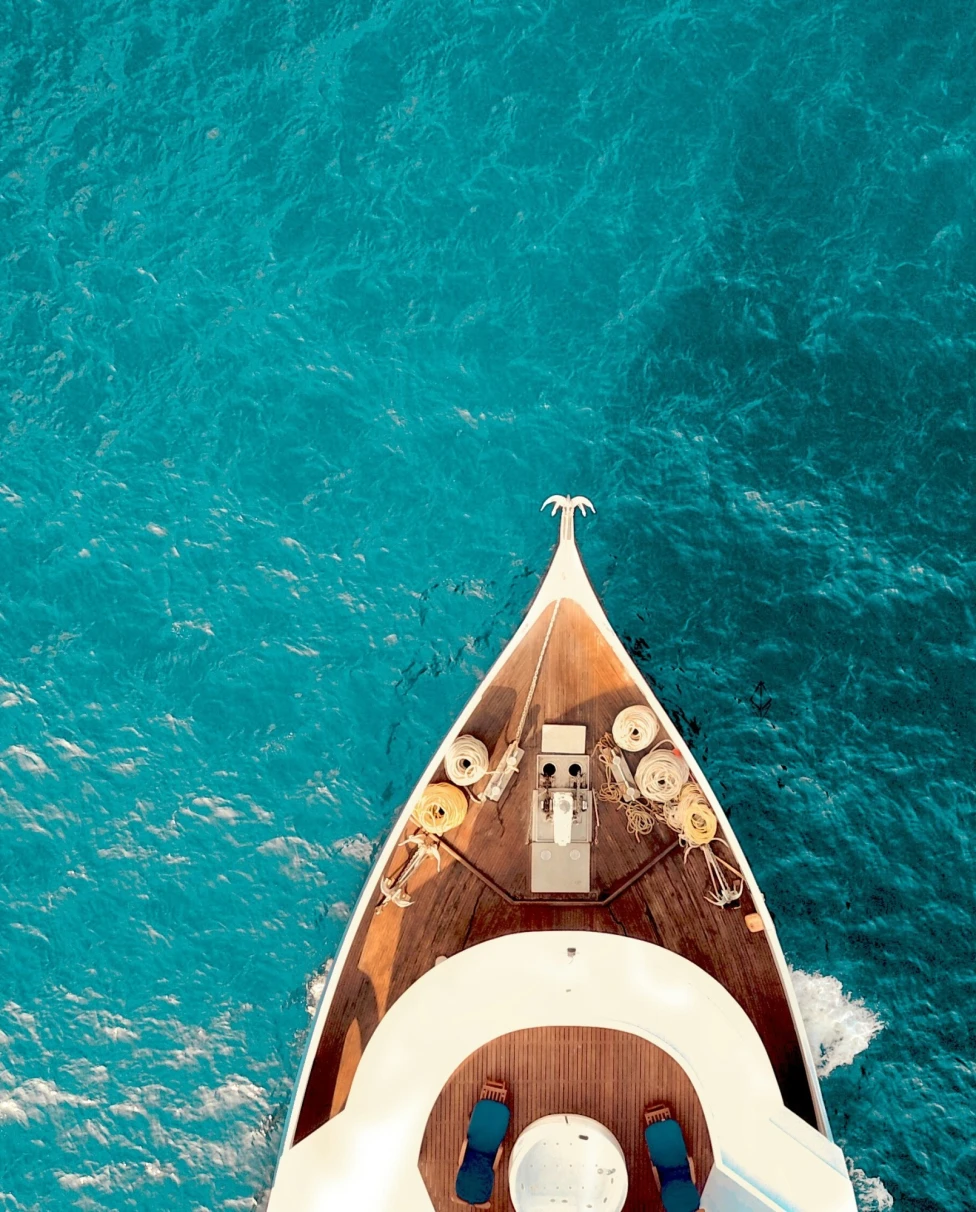 The image captures the essence of adventure with a boat’s bow slicing through the serene blue waters.
