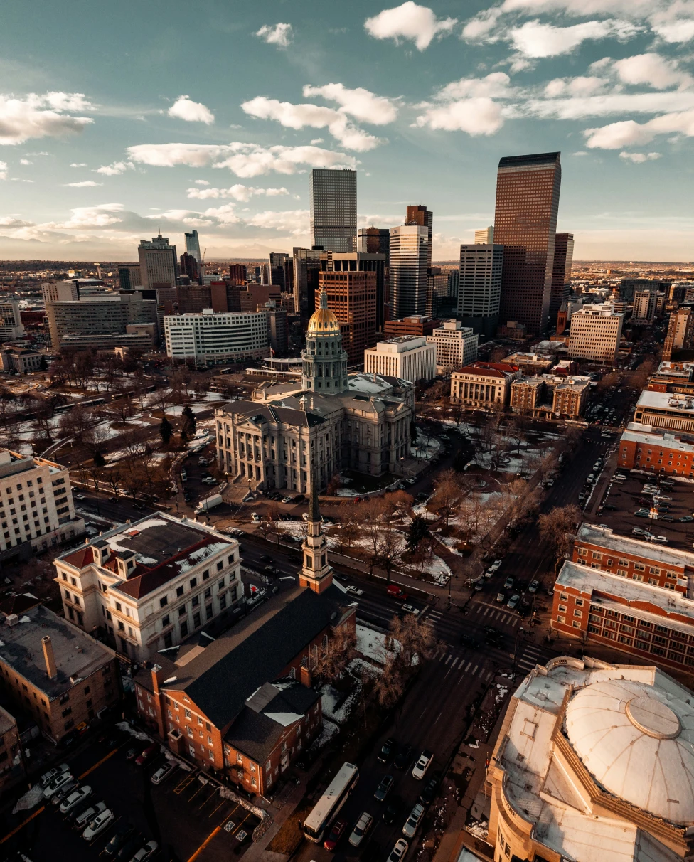 The Denver skyline with tall buildings on a sunny day with clouds.