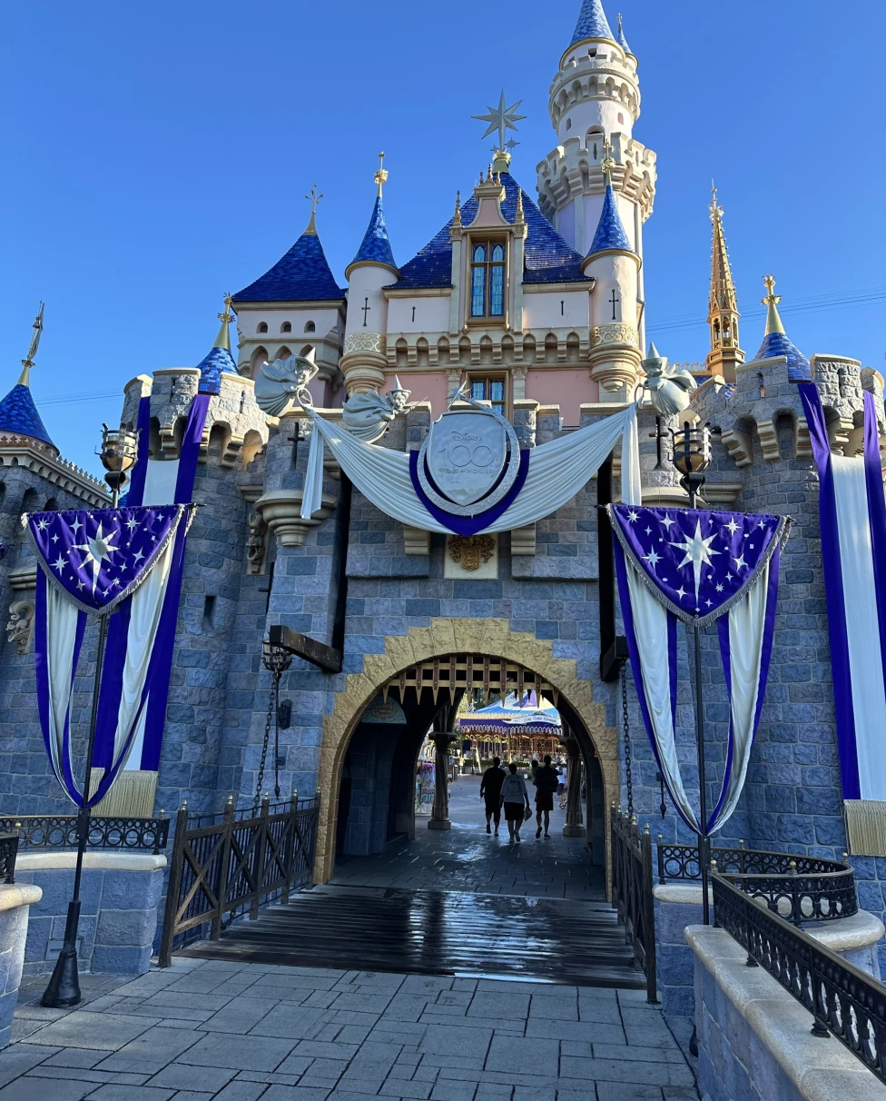 A castle with blue and gold turrets, adorned with star-spangled banners, under a clear blue sky.