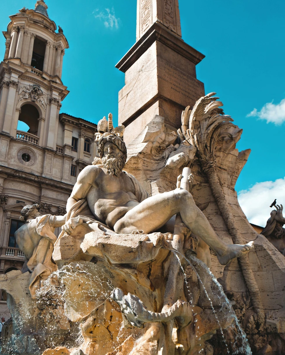 Piazza Navona, with a fountain sculpture in front of an ancient building on a clear blue day, one of the attractions in Rome, Italy.