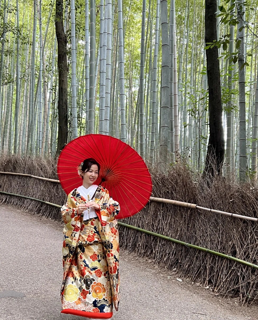 A woman in traditional Japanese dress holding a red umbrella.