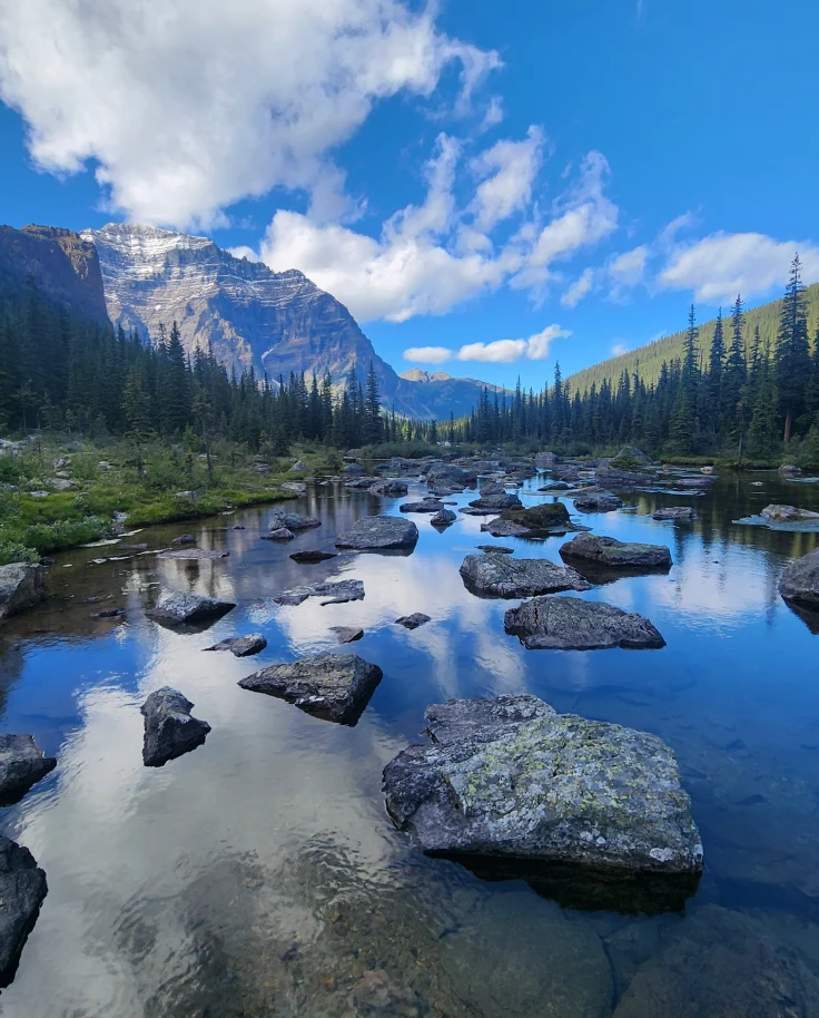 A scenic view of a turquoise-colored lake between mountain ranges during the daytime