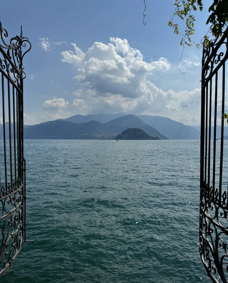 Two black gates open to reveal a lake with mountains in the distance