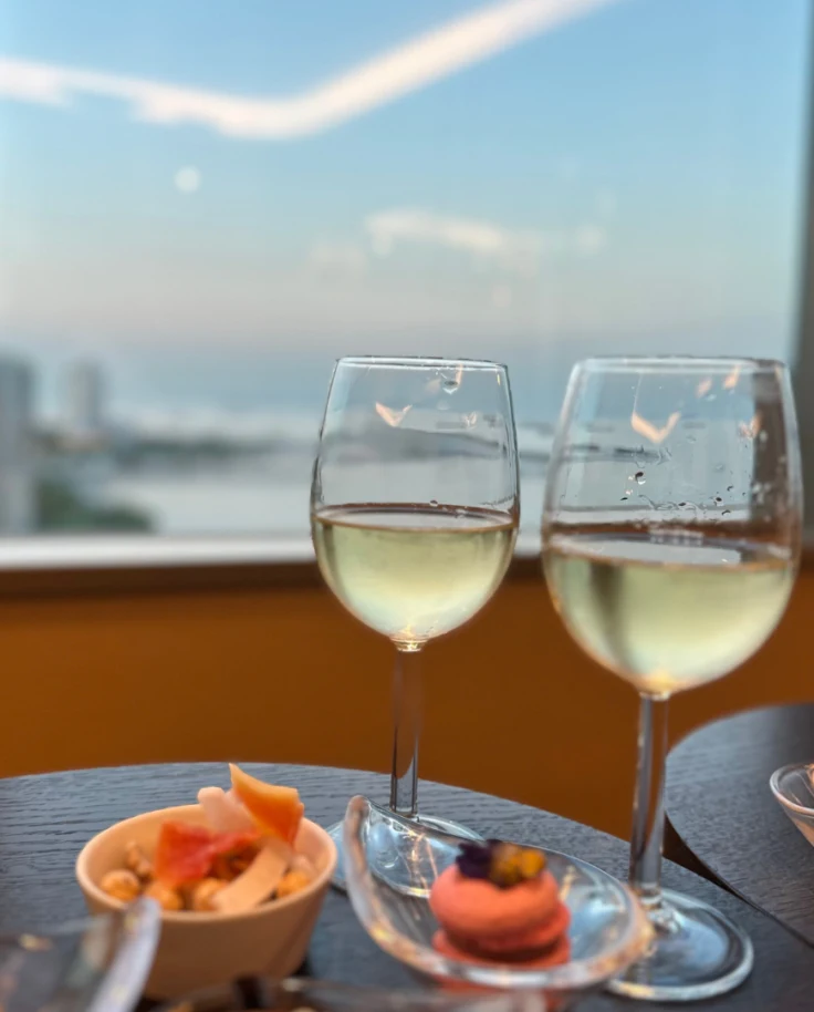 Two wine glasses holding white wine sitting in a table