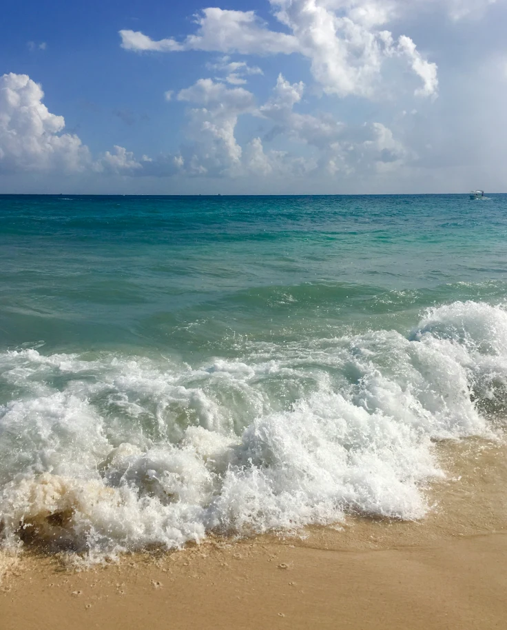 A white sand beach with blue waves crashing on shore outside of the Hotel Riu Palace Riviera Maya Mexico - Playa del Carmen.