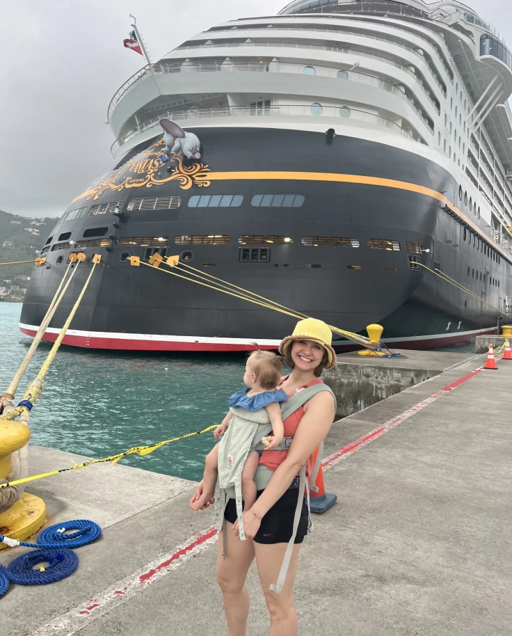 Travel advisor and baby posing before the Disney Cruise Ship at port on a cloudy day.