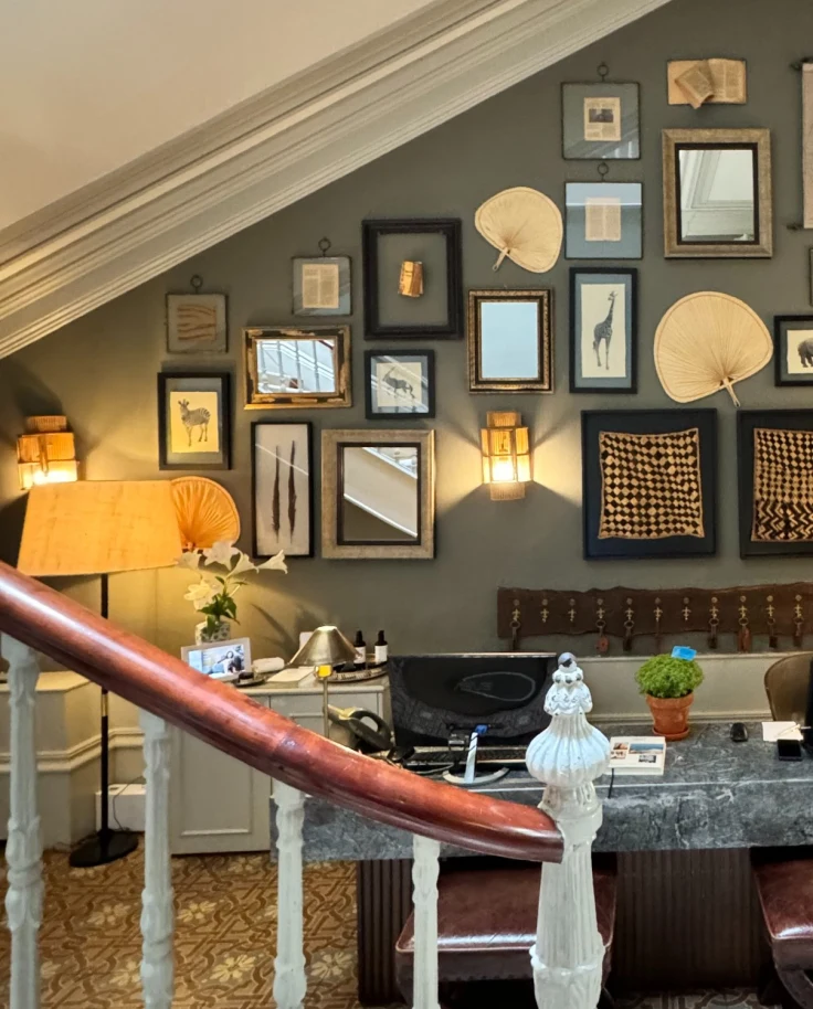 A reception desk of a hotel against a wall with multiple pieces of artwork