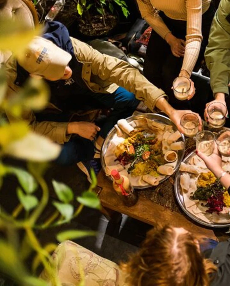 A view from above of a group of people sharing a meal and holding their glasses out to toast.during a food tour in Cape Town.