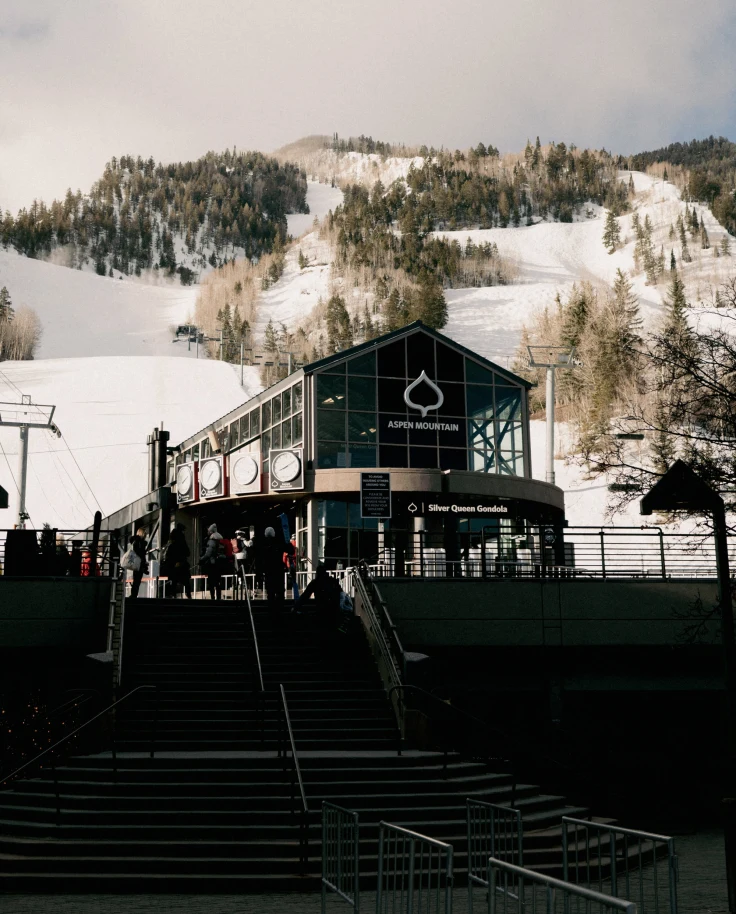 A cabin at the bottom of a snow-covered hill during the daytime