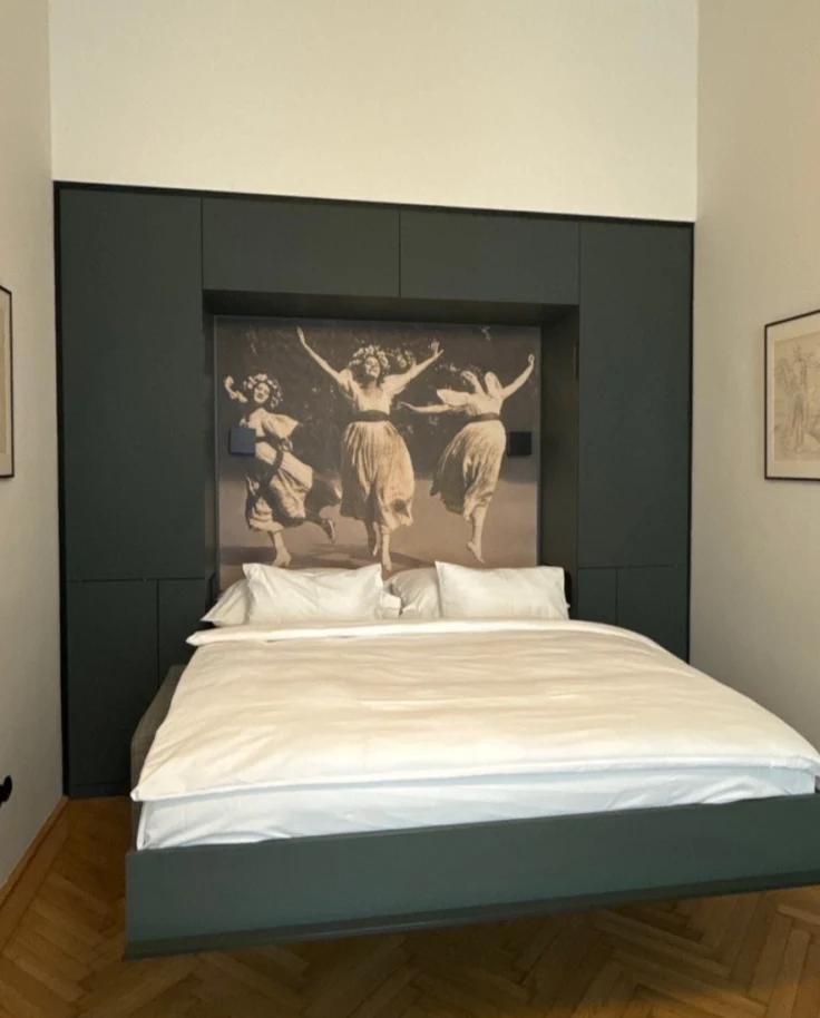A bed in the center of a hotel room, pushed against a back wall with a large photograph above it