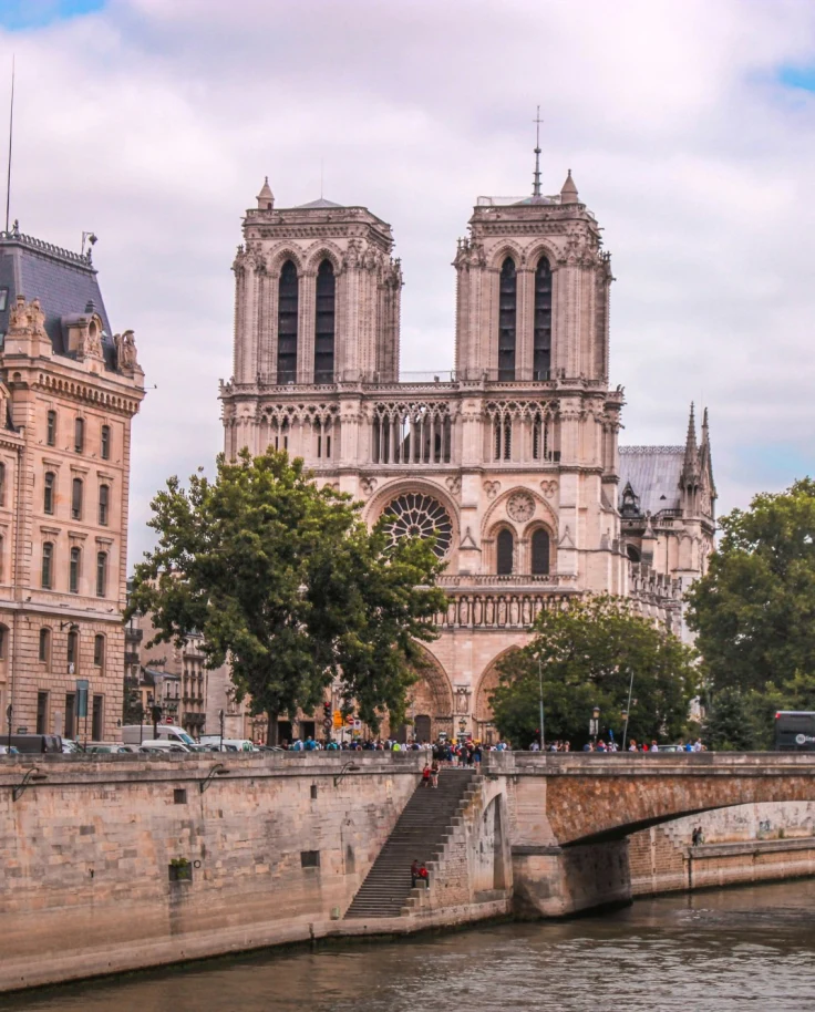 The Notre-Dame Cathedral near the Seine and Paris 4th arrondissement hotels on a sunny day.