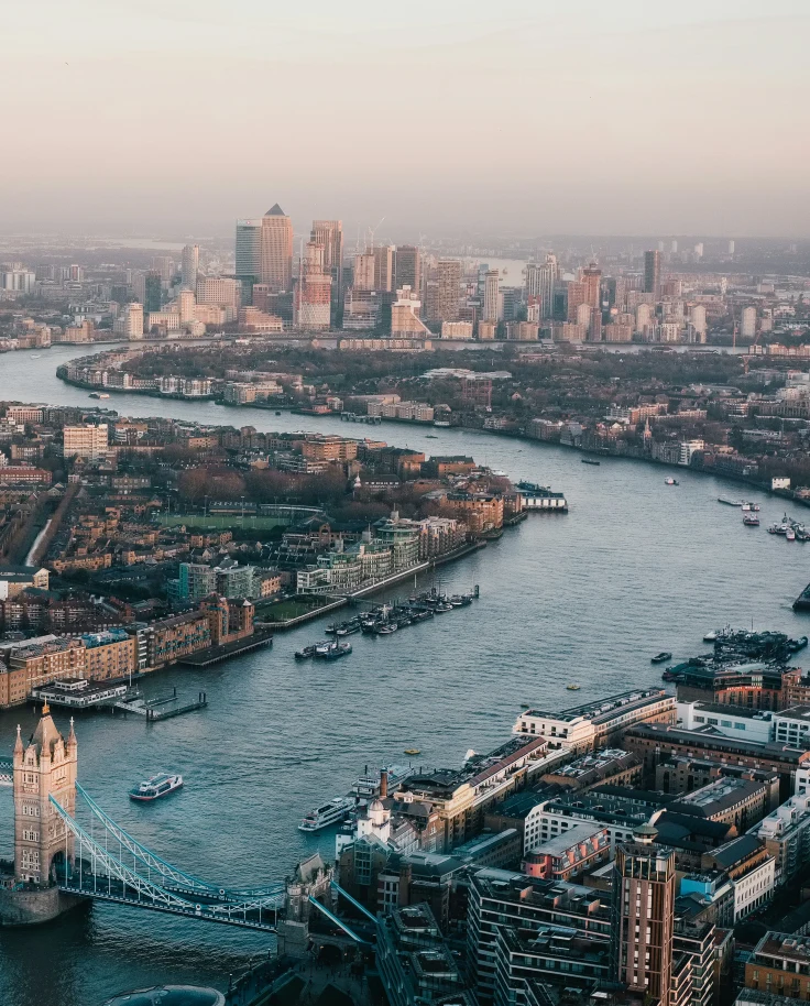 An aerial view of London's River Thames, the Tower London, and skyline bending around the curvy river.
