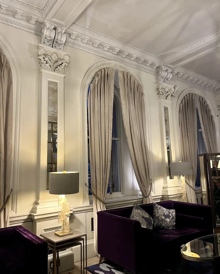 An indoor room with tall, arched windows and dark furniture