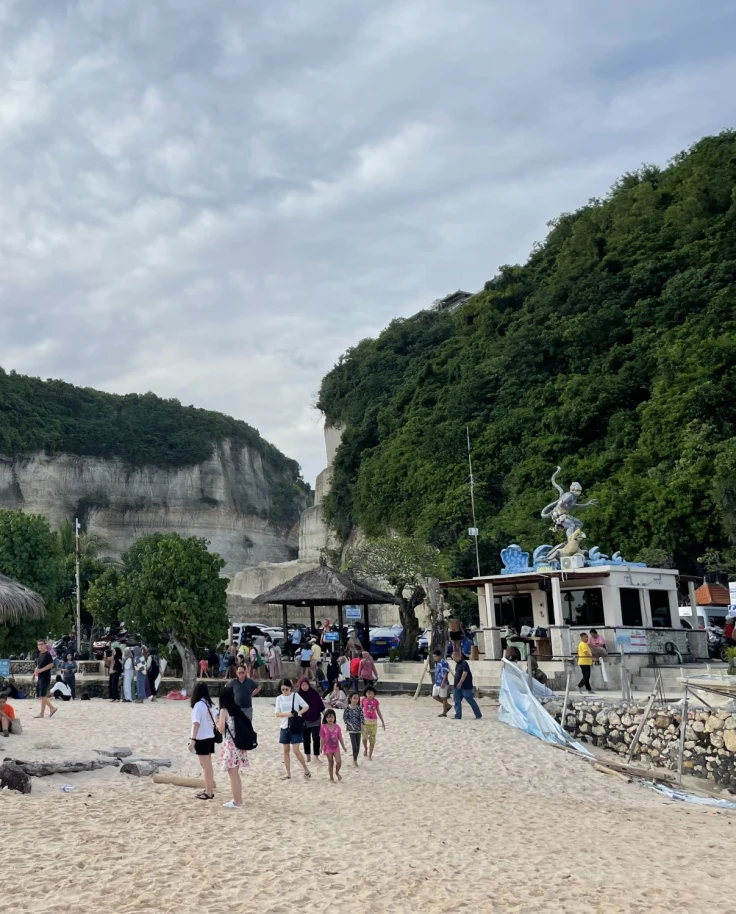 A beach during the daytime with cliffs in the background
