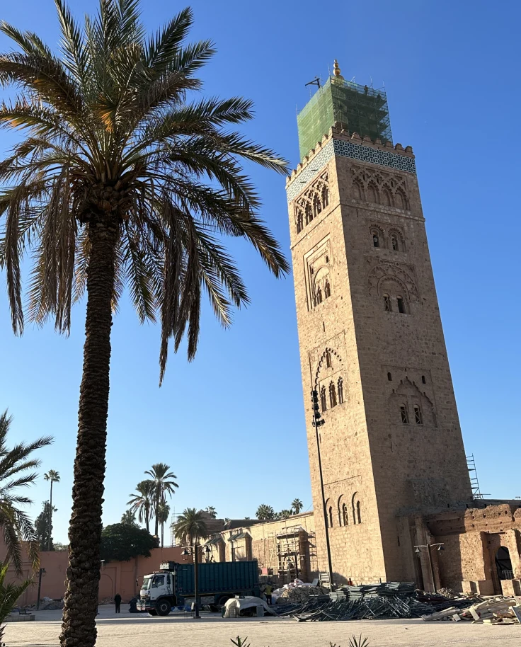 A low-abled view of a tall building next to a palm tree during the daytime