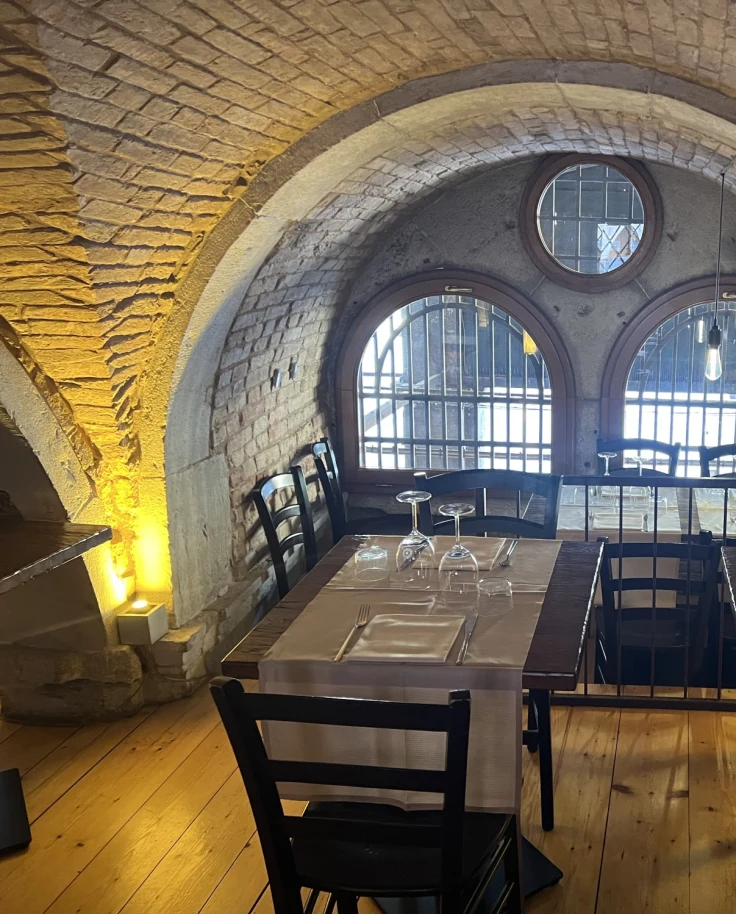 A dining area in a dimly lit room with arched windows