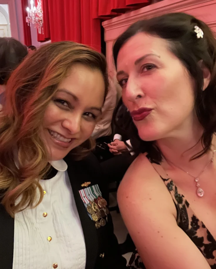 April in a military officer's outfit taking a selfie with a woman in a dress at the ball